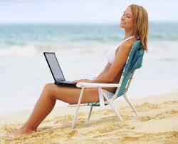 Young woman working on a laptop on a beech.